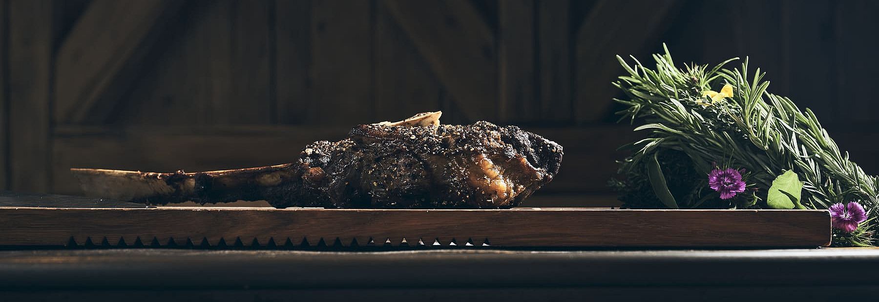 Gegrilltes Tomahawk Steak auf einem Schneidebrett mit frischem Rosmarin