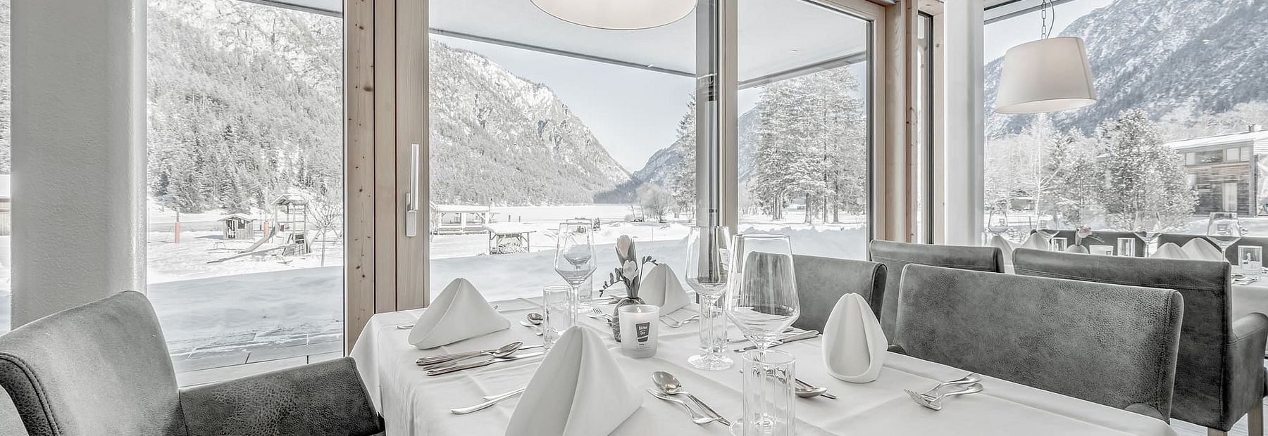 Gedeckte Tische in einem Restaurant mit Blick auf die verschneite Landschaft im Winter