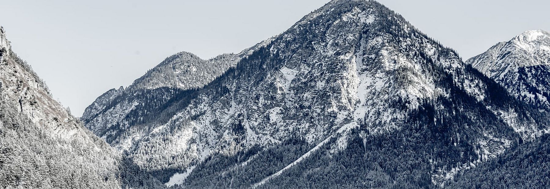Verschneites Bergpanorama und Wald am Heiterwanger See im Winter