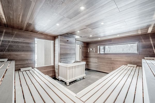 Helle Holzsauna mit großem Fenster und Blick auf verschneite Winterlandschaft