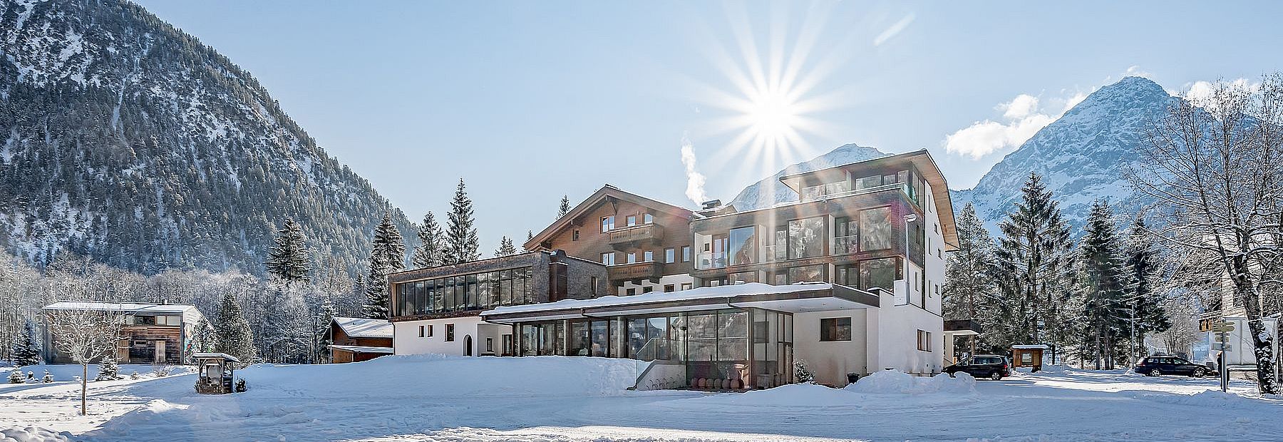 Hotel Fischer am See im Winter bei Sonnenschein mit Blick auf die verschneiten Berge