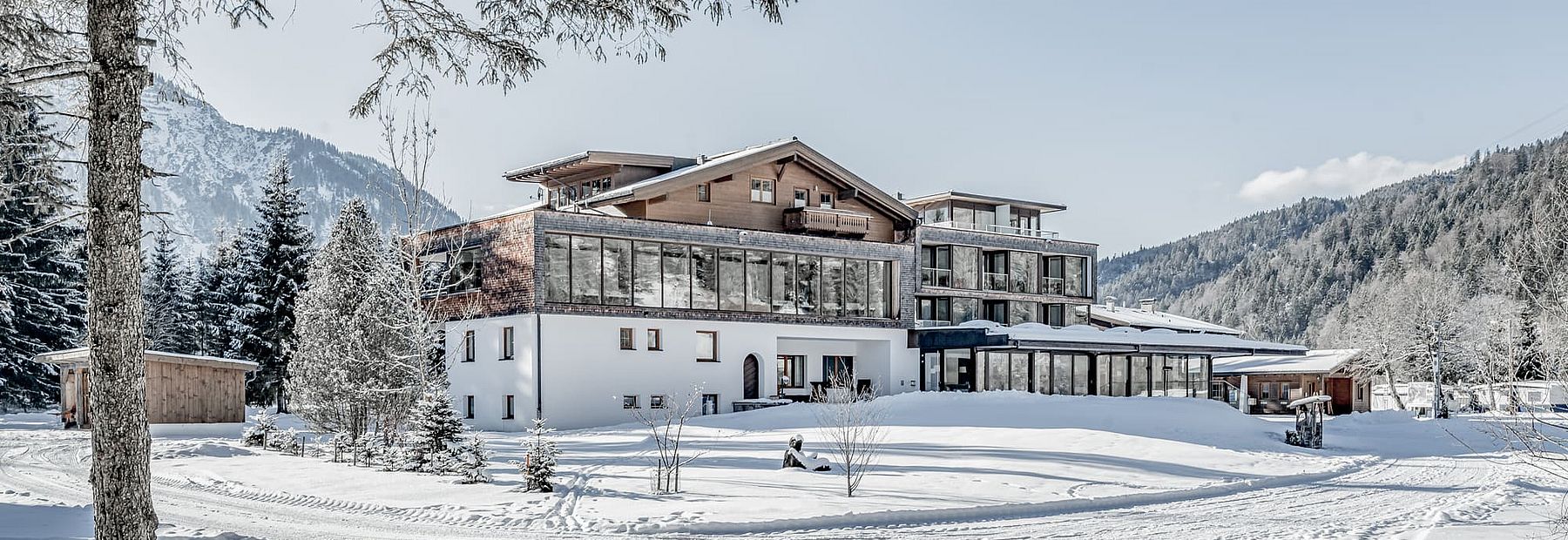 Hotel Fischer am See in verschneiter Winterlandschaft und Bergpanorama