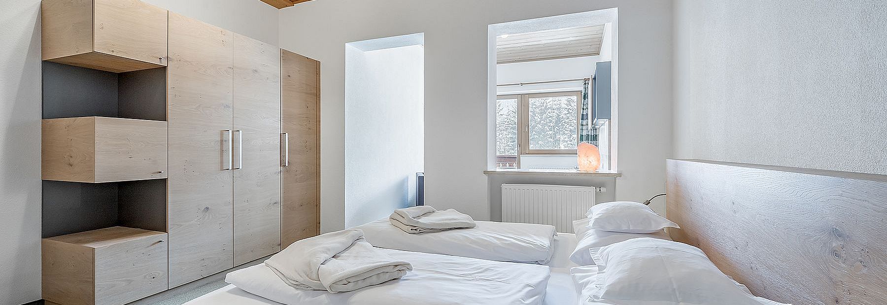 Doppelbett und Wandschrank in einem Hotelzimmer mit Holzdecke mit abgetrenntem Wohnbereich 