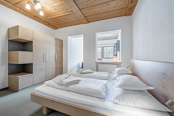 Doppelbett und Wandschrank in einem Hotelzimmer mit Holzdecke mit abgetrenntem Wohnbereich 